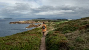 a woman with a backpack walks along a costal path in Ayrshire