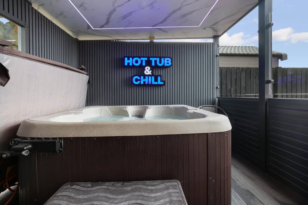 Hot tub at Pod 6 with a neon sign reading Hot Tub and Chill